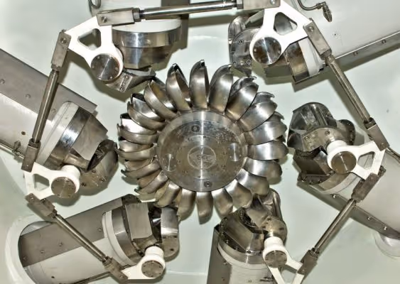 Close-up of a metallic mechanical assembly featuring a central circular part with curved blades surrounded by six adjustable arms with cylindrical components.
