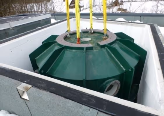 Large green industrial pump or motor installed in a concrete pit with yellow lifting straps above it.