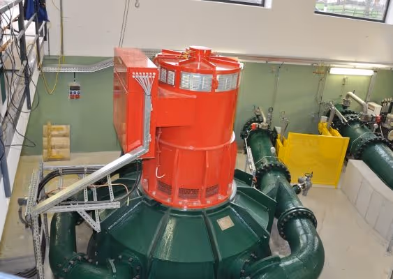 Industrial machinery with a large green base and a prominent red cylindrical component inside a facility.