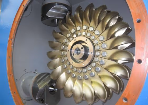Close-up of a metallic turbine wheel with curved blades inside a blue and orange housing.