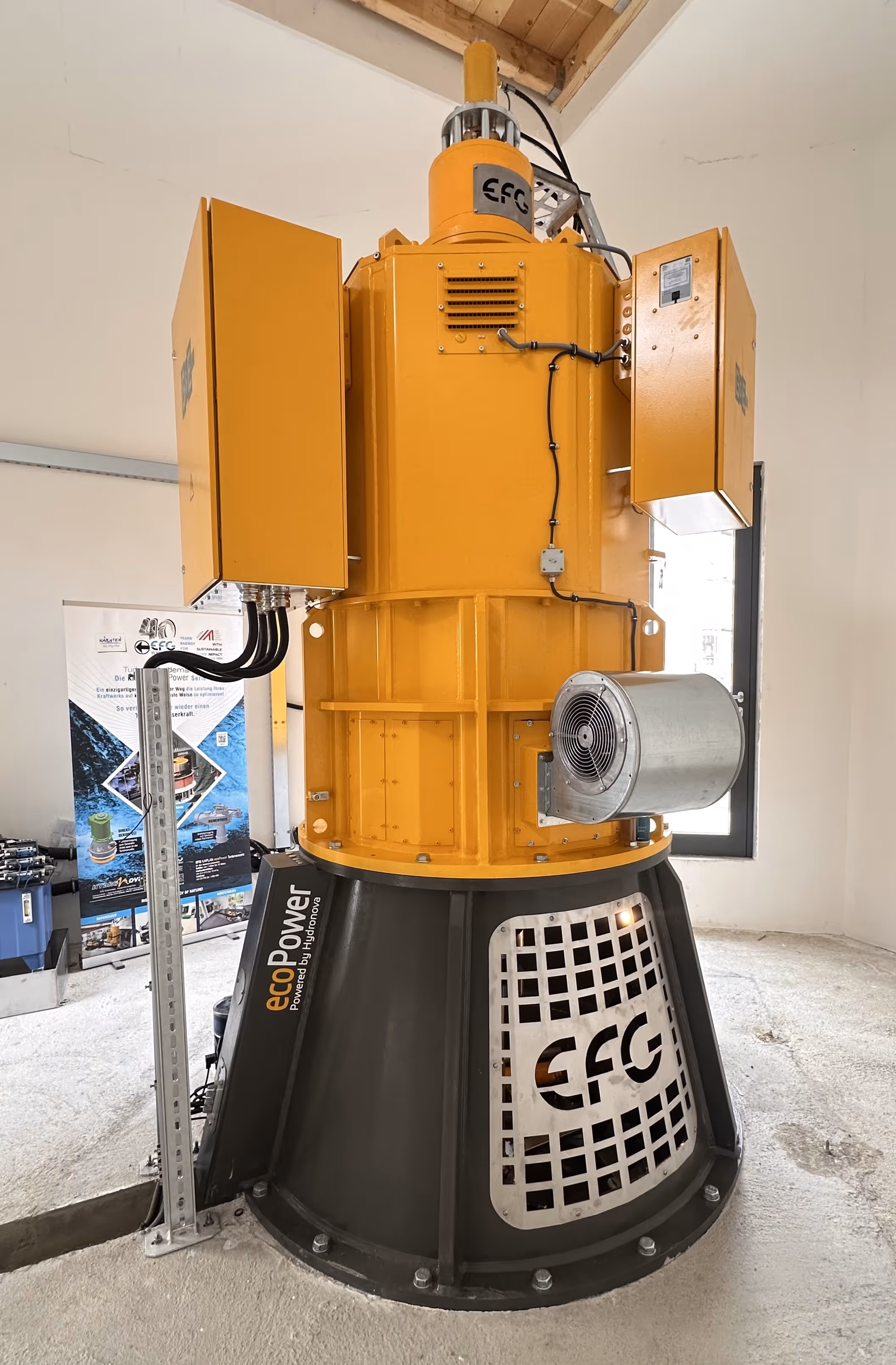 Large industrial ecoPower generator unit with yellow upper section and black base inside a room.