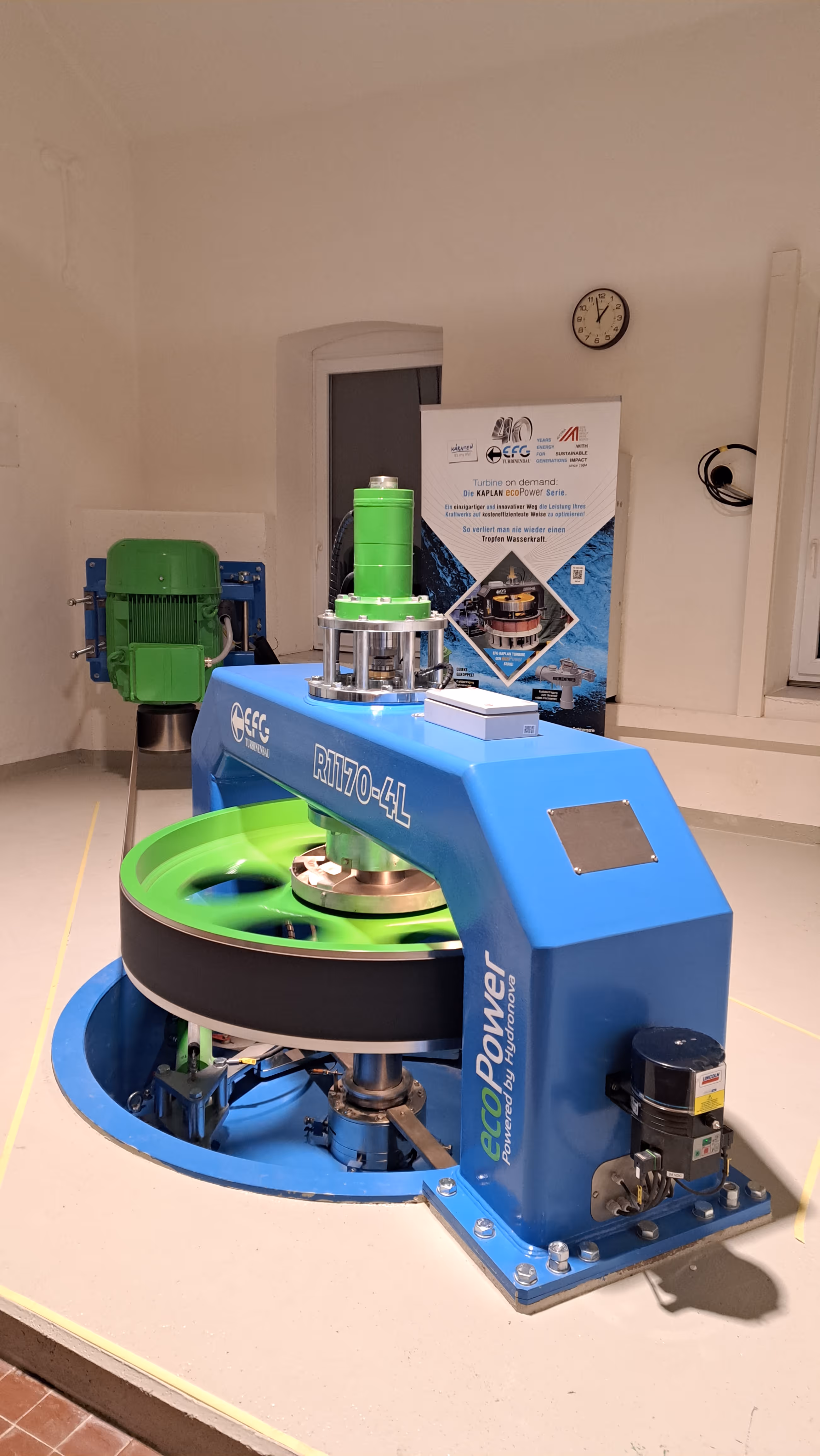 Blue and green hydroelectric turbine model R1170-4L with ecoPower branding on display indoors.