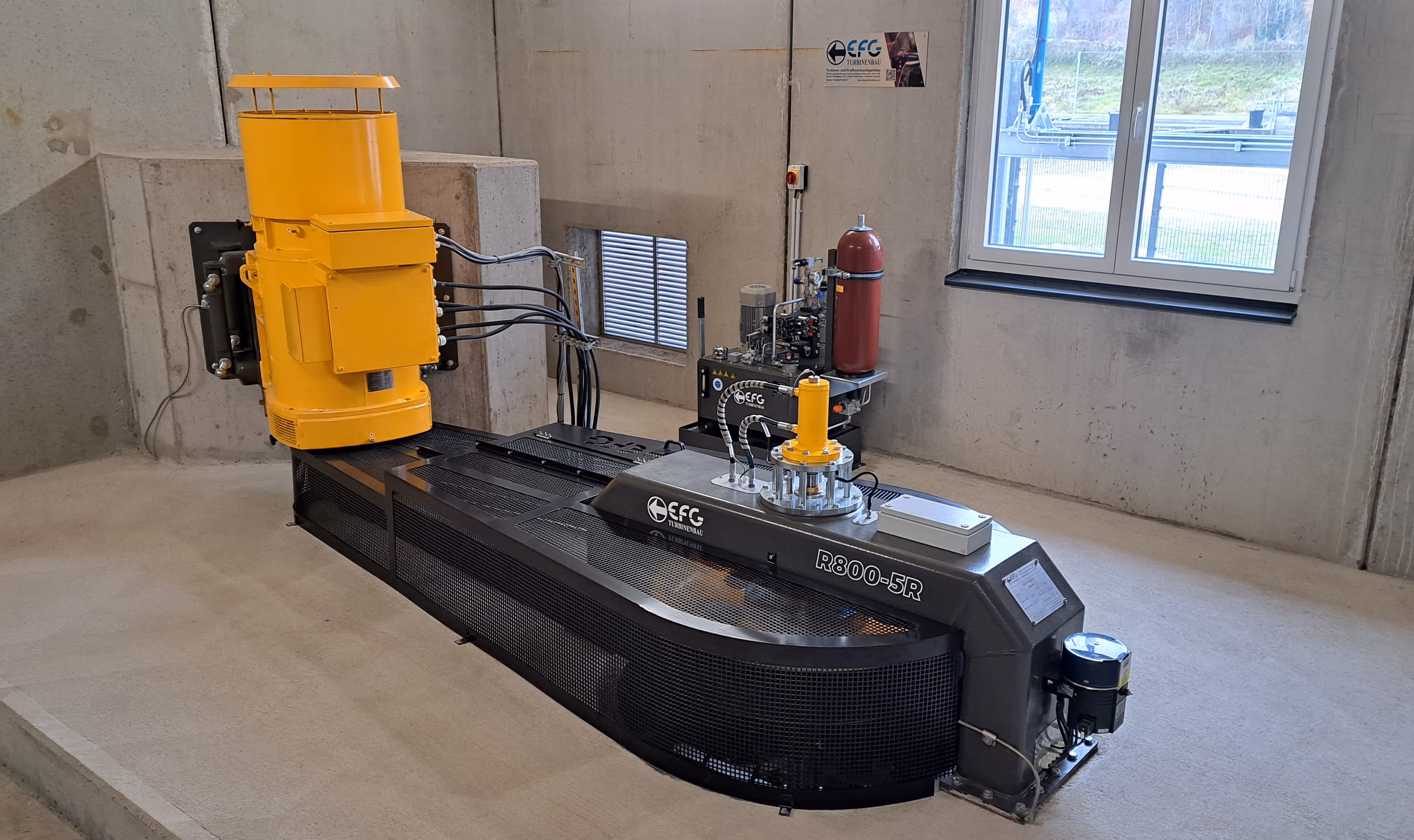 Industrial turbine testing machine labeled R800-5R with yellow components in a concrete room with a window.
