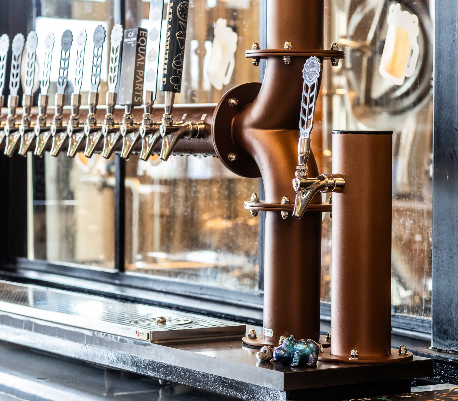 Close-up of a brown beer tap system with multiple silver handles lined up, located on a bar counter.