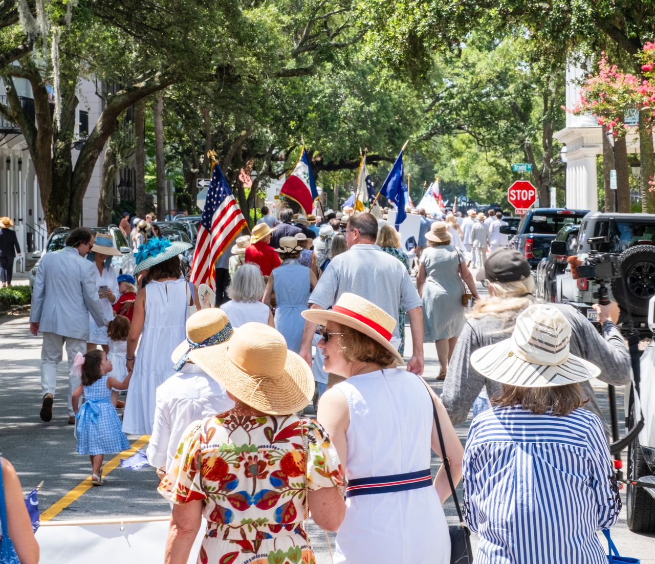 Historical reenactors in colonial uniforms firing muskets behind a stone wall with visible gunfire and smoke.