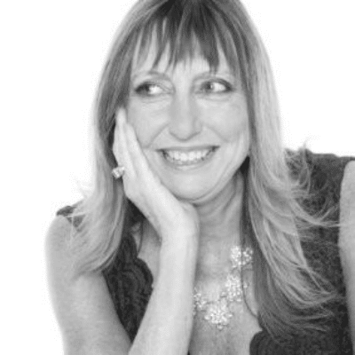 Black and white portrait of a smiling woman resting her face on her hand, looking to the side.