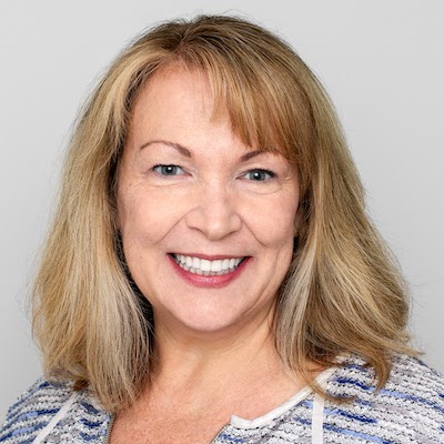 Smiling middle-aged woman with shoulder-length blonde hair and blue and white top.