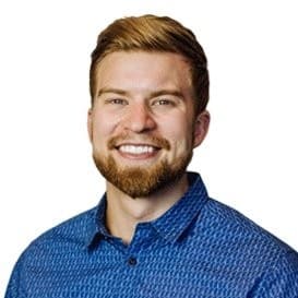 Smiling man with blond hair and beard wearing a blue patterned button-up shirt.