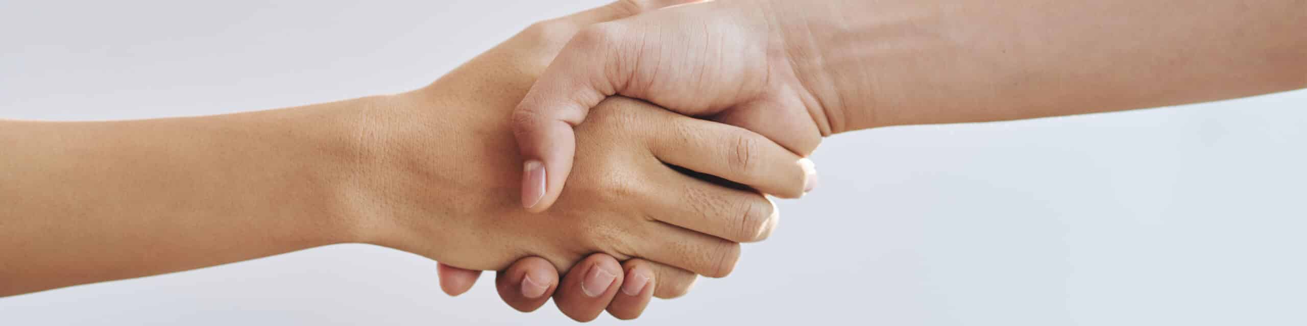 Two people shaking hands showing a gesture of agreement or partnership.