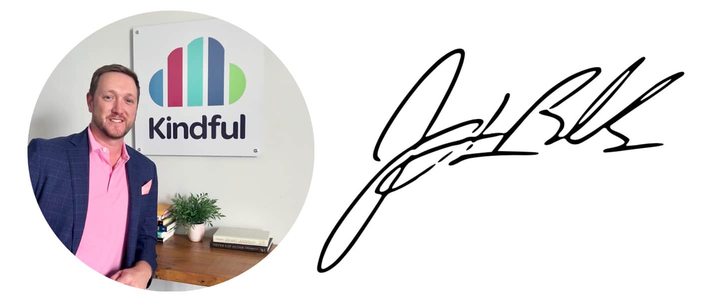 Man in pink shirt and navy blazer standing by a desk with a Kindful logo sign behind him and a signature to the right.