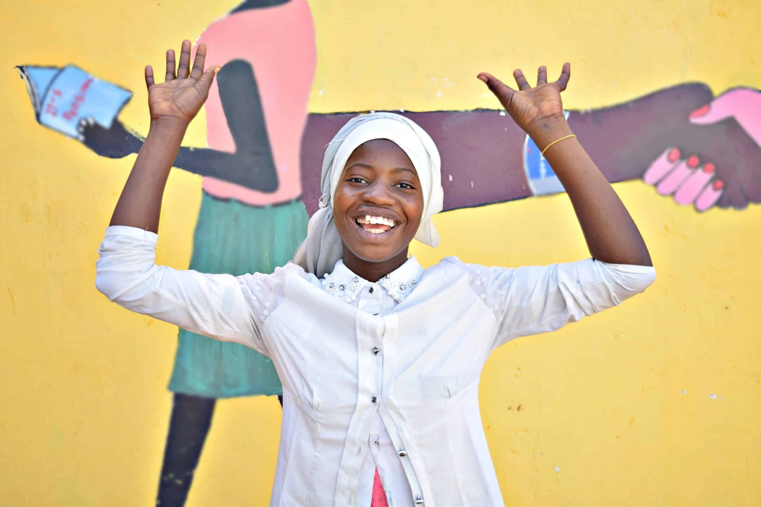 image from shes the first website with smiling girl in front of bright yellow wall