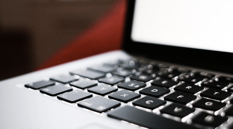 Close-up of a laptop keyboard with black keys showing letters and symbols.