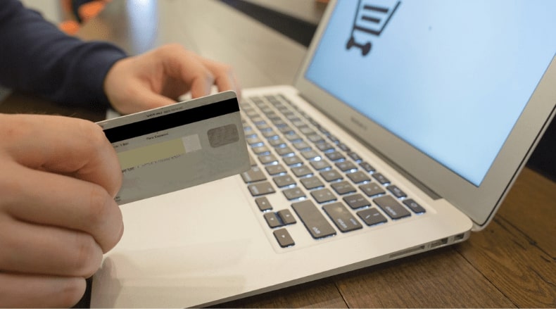 Person holding a credit card and using a laptop for online payment or shopping.