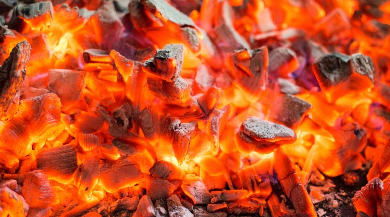 Close-up view of glowing hot orange and red embers with dark gray ashes.