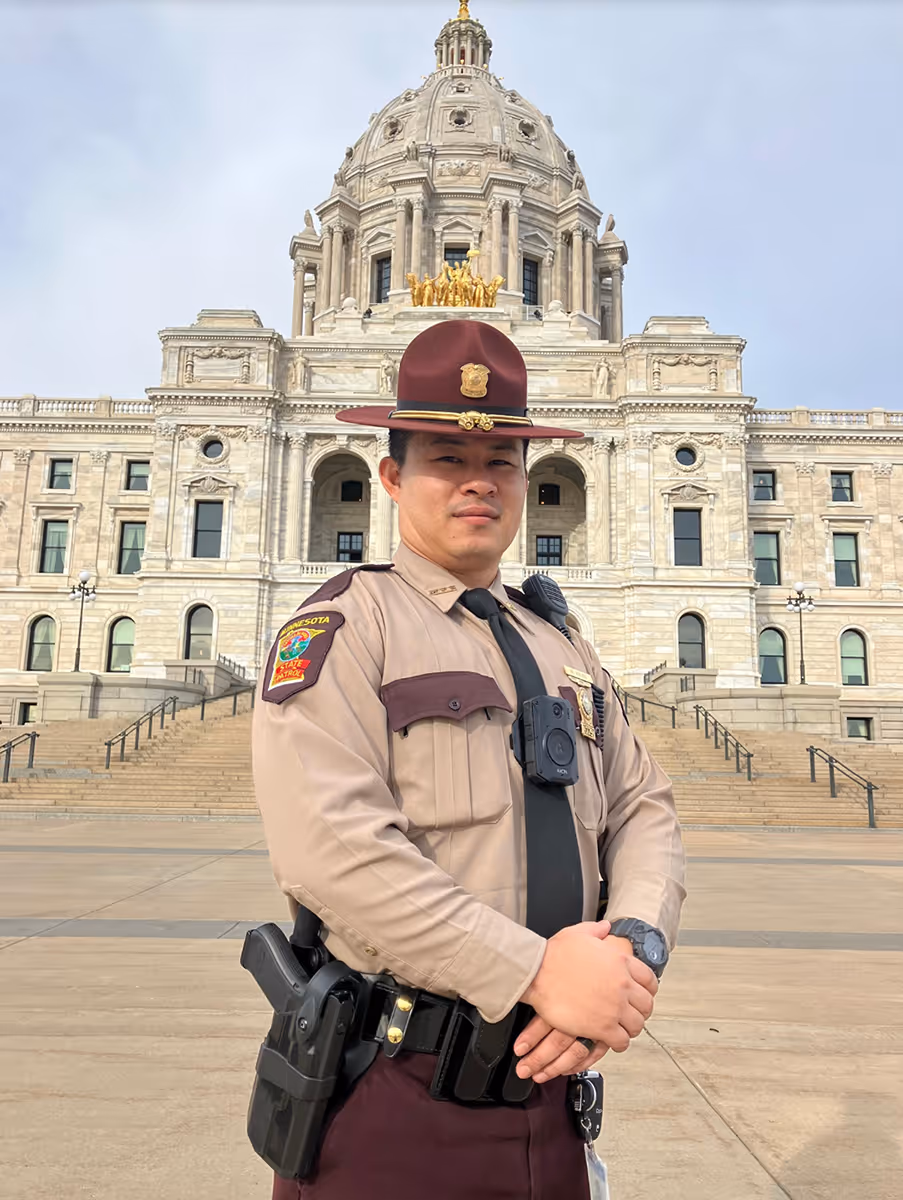Minnesota state trooper in uniform standing in front of the Minnesota State Capitol building.