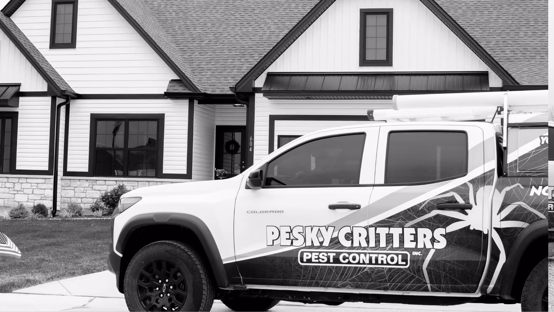 Pickup truck with Pesky Critters Pest Control logo parked in front of a modern house.