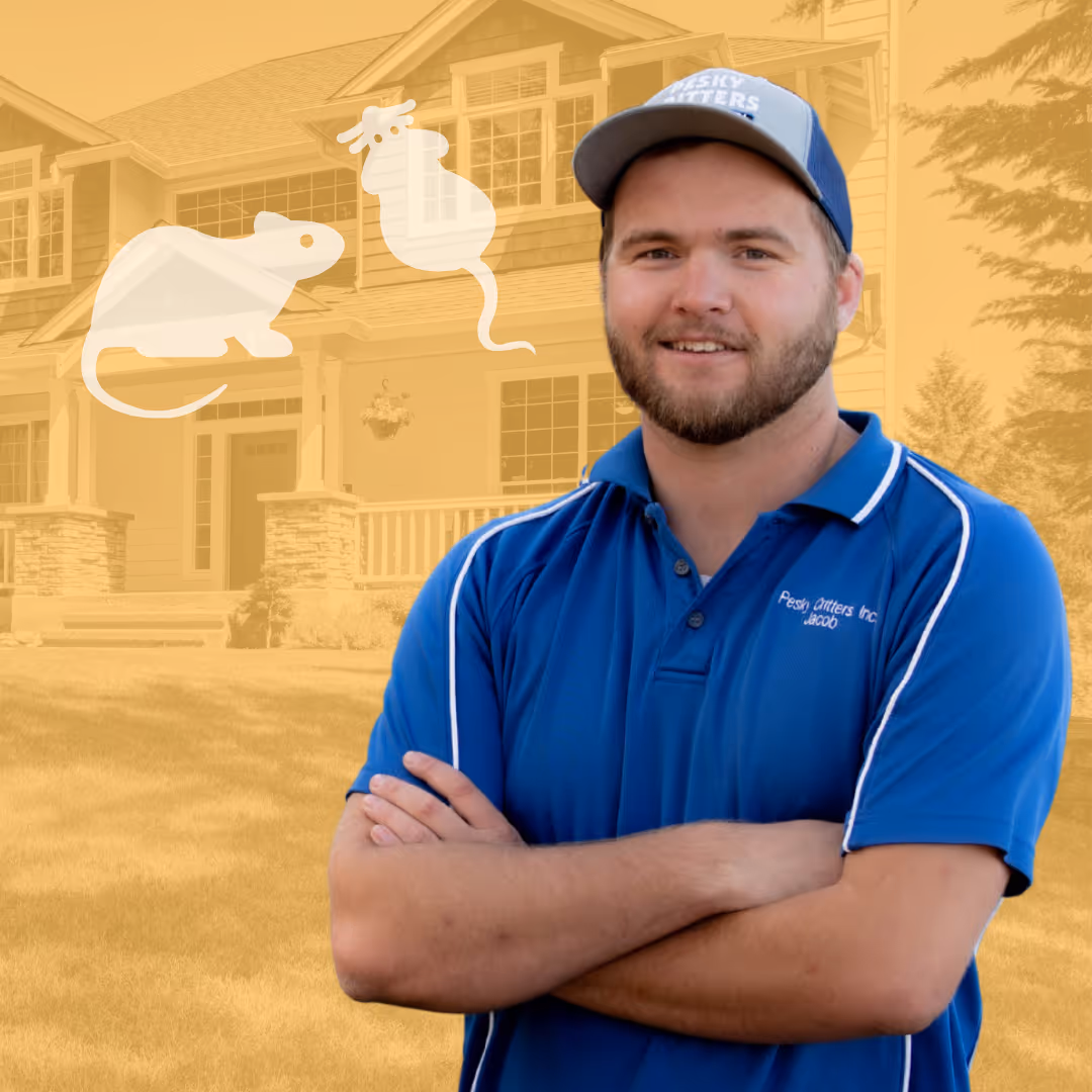 Smiling pest control technician wearing a blue shirt and cap standing with crossed arms in front of a house with rodent illustrations.