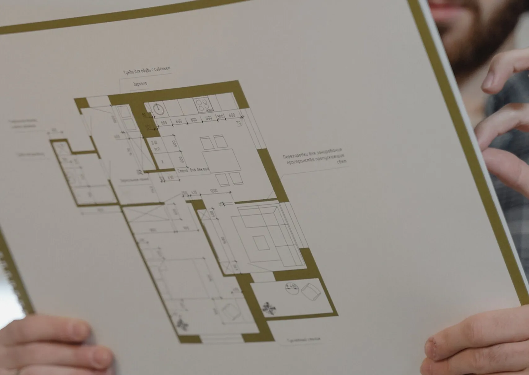 Close-up of hands holding a floor plan with labeled room layouts and measurements.
