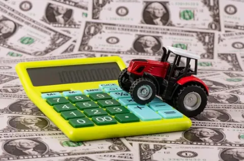 small tractor on a calculator and money pile