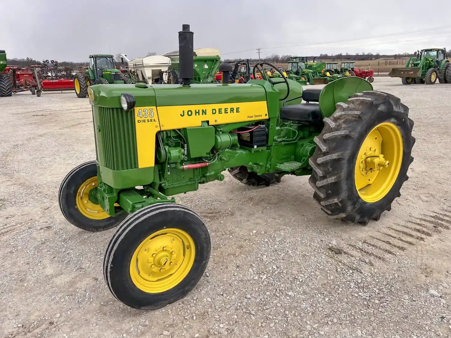 A green John Deere tractor displayed outdoors on gravel