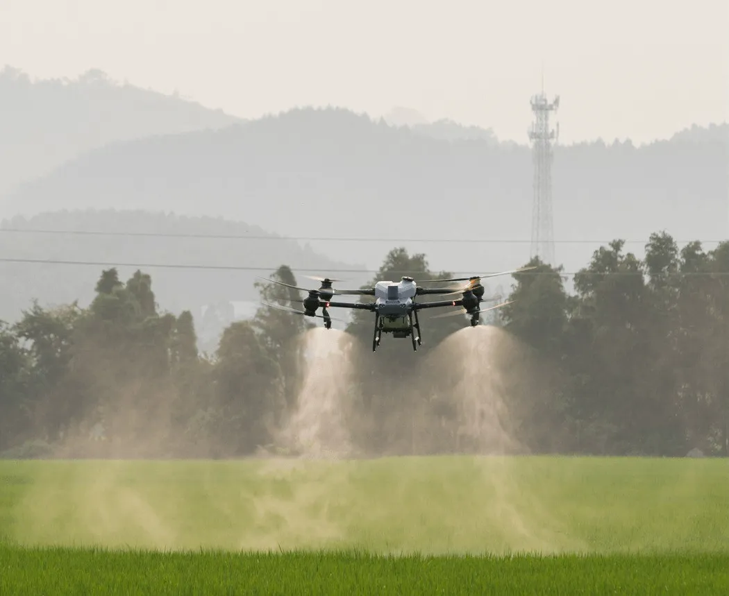 A drone spraying crops in a field with a mist of liquid coming from its sprayers