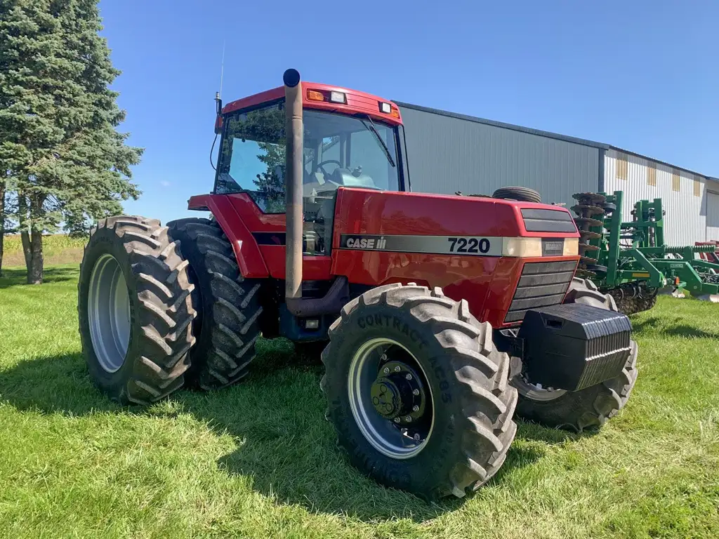 A Case IH 7220 tractor parked on a field near a building