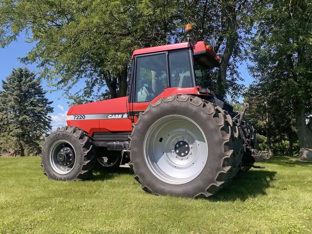 A red tractor parked on a grassy area with trees in the background