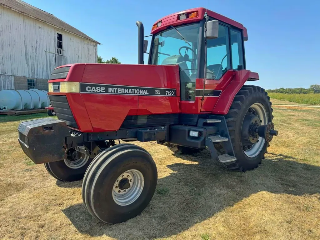 A Case International 5120 tractor parked on a grassy area near a barn