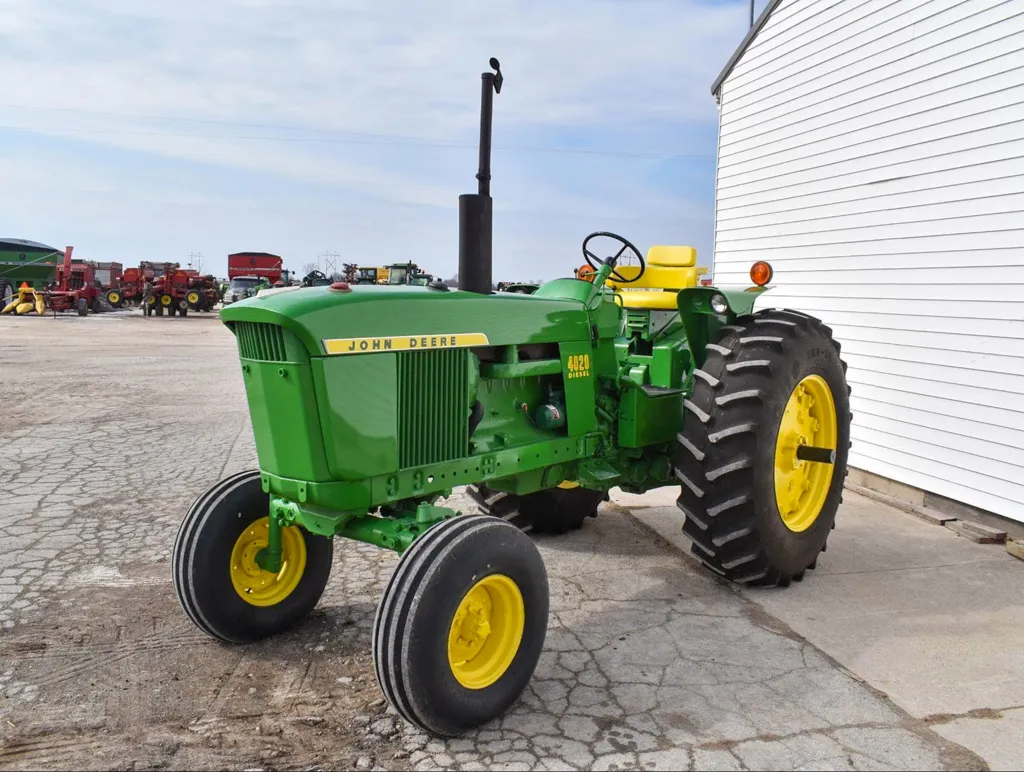 A green agricultural tractor parked near a white building