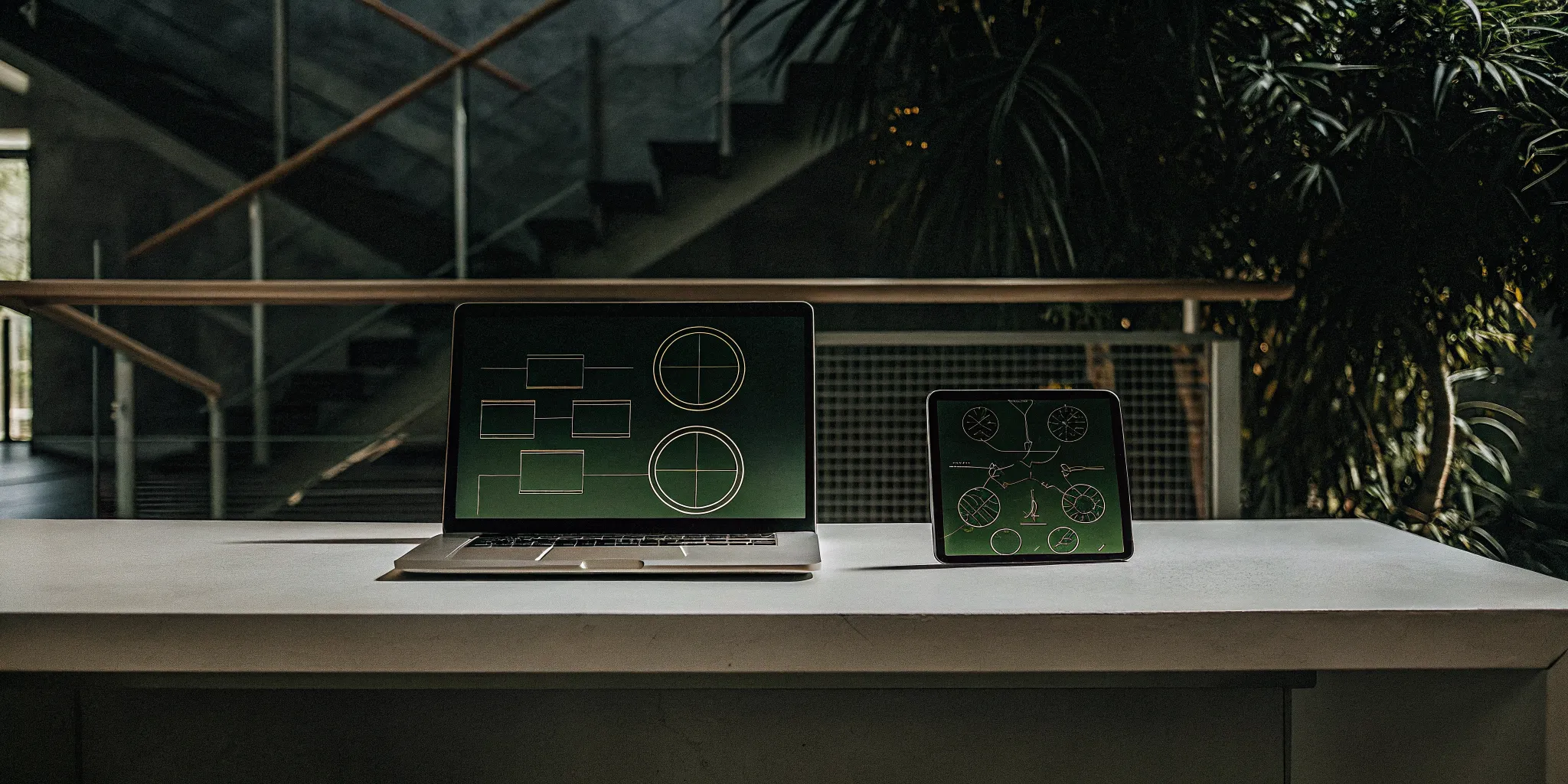 A laptop and tablet on a desk displaying the best apps for manager development.