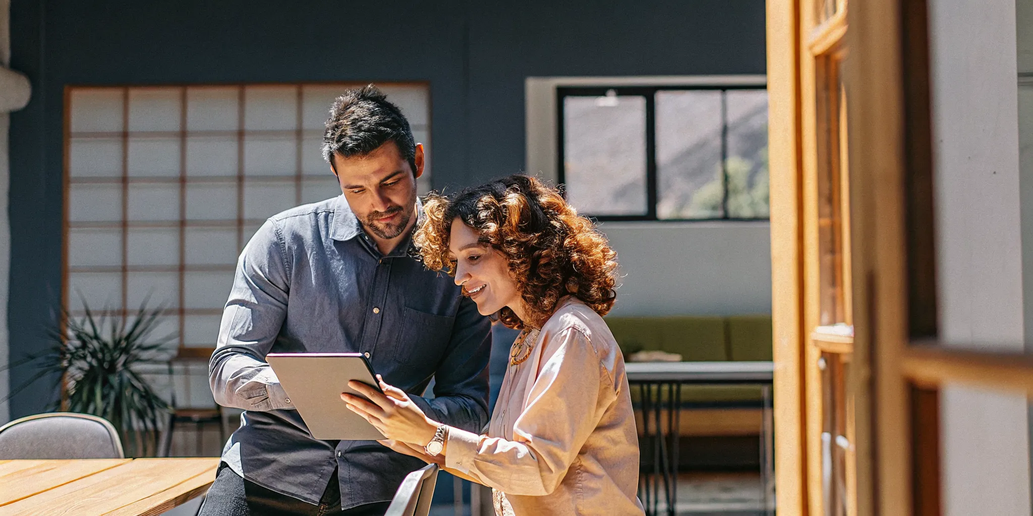 A manager and employee reviewing a professional development plan on a tablet together in an open collaborative workspace