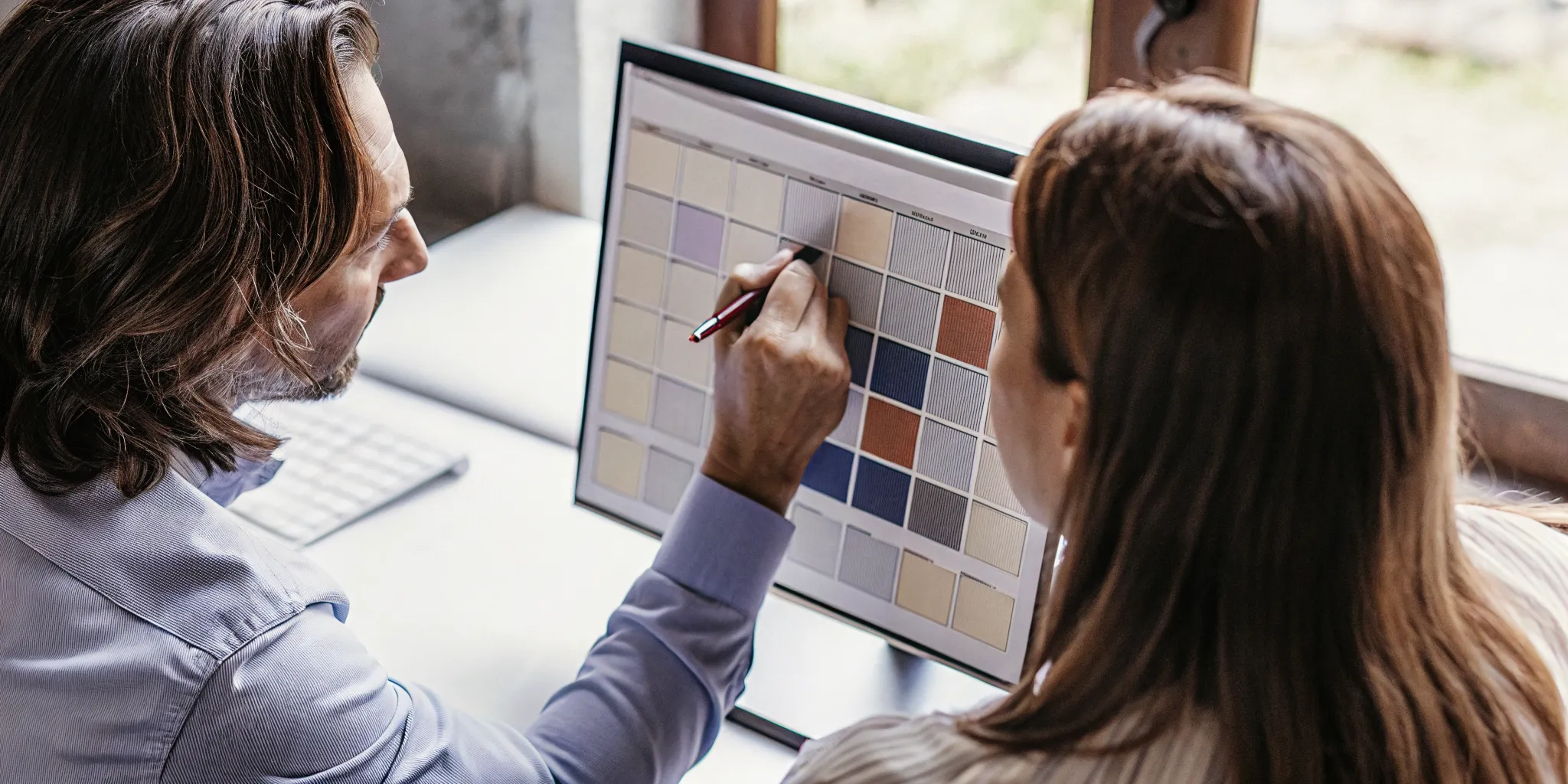 A manager and team member analyzing a color-coded calendar dashboard together