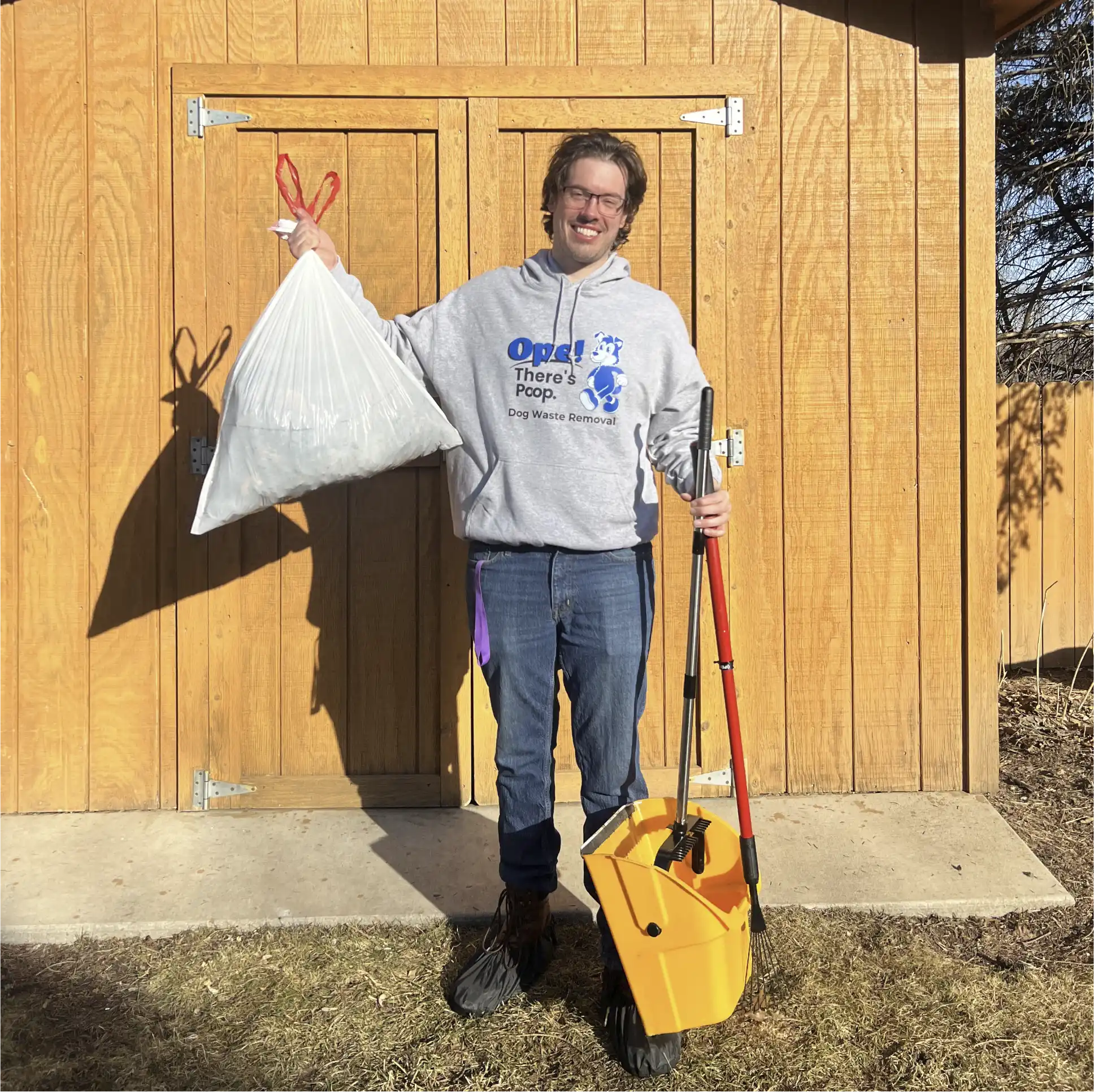 David - the owner of Ope There's Poop, on the job in St. Paul, MN - holding a trash bag and a pooper scooper. 