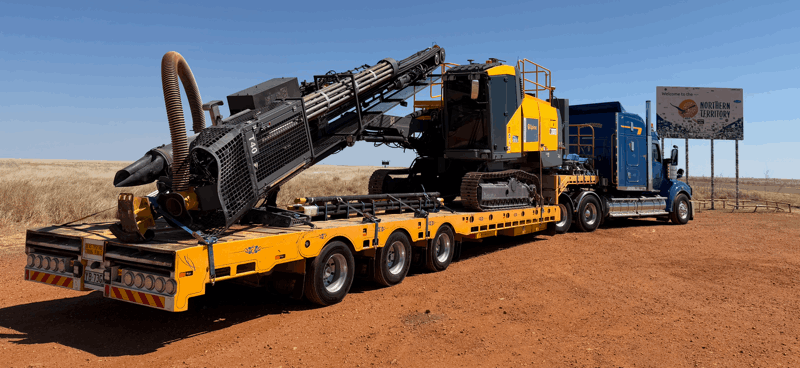 Yellow and black Epiroc T40 drilling machine on a red flatbed trailer in a rocky outdoor area.