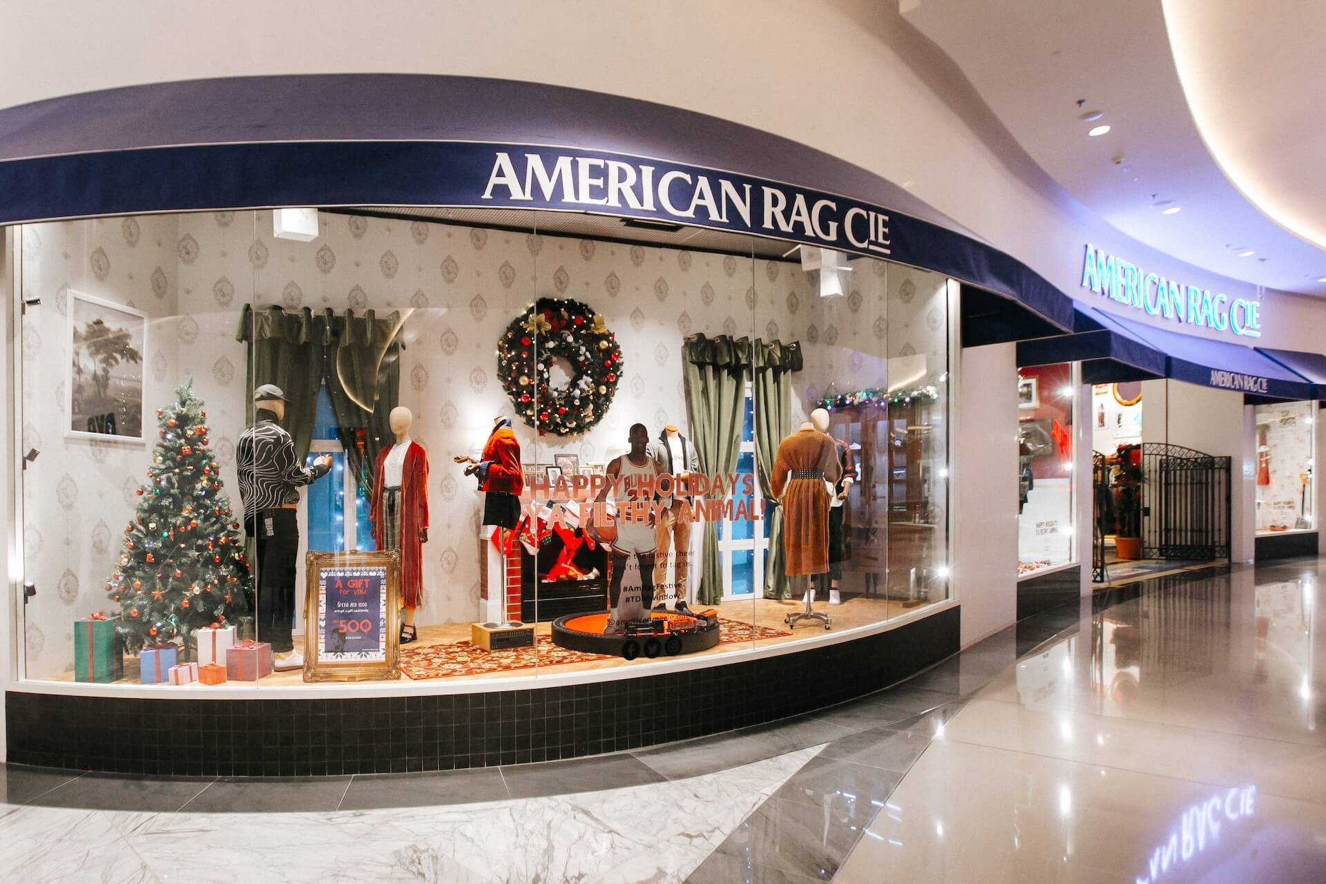 American Rag Cie storefront with holiday decorations and dressed mannequins in mall