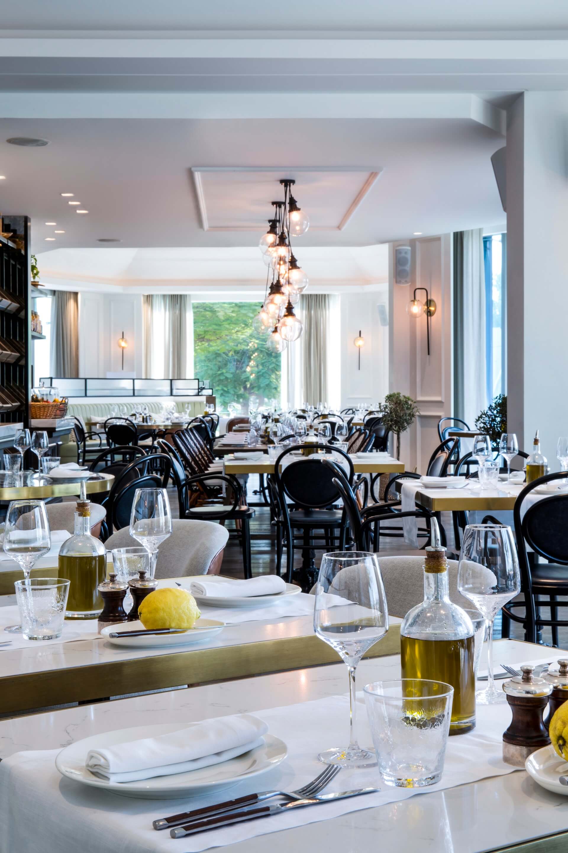 Elegant upscale restaurant dining room with set tables, pendant lights, and views