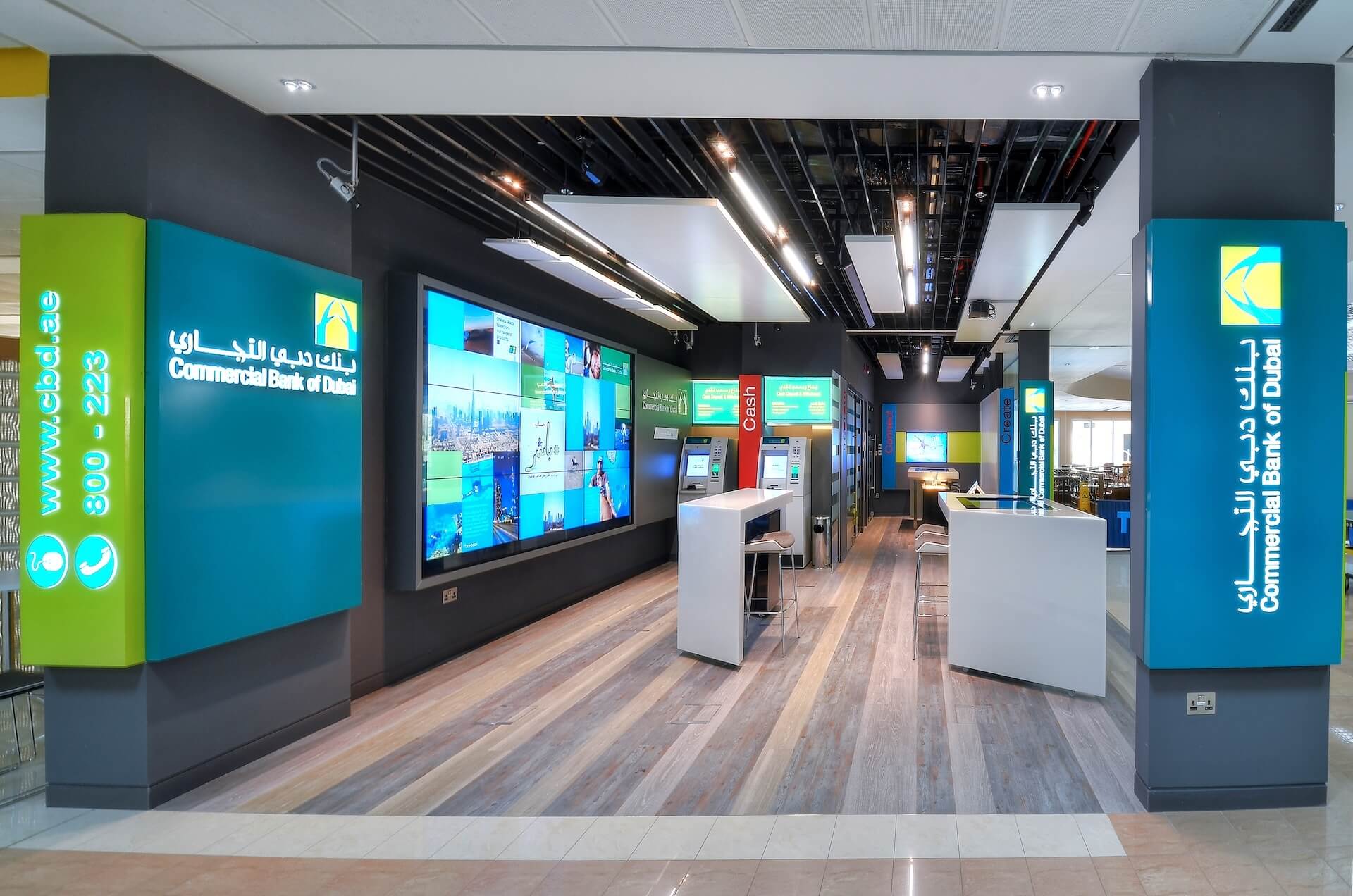 Modern Commercial Bank of Dubai branch interior with digital displays, service counters, and green and teal branding