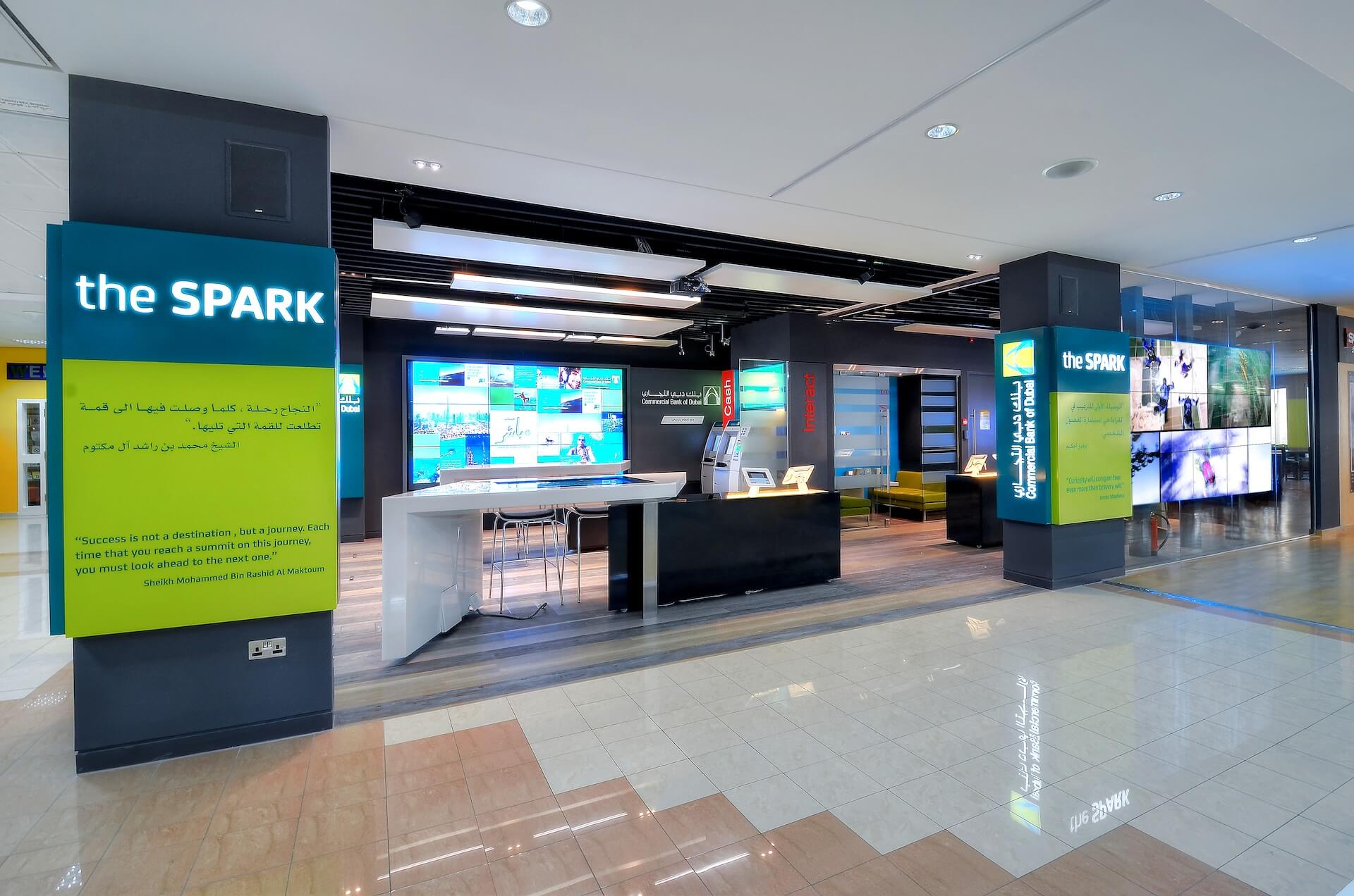 Modern "The Spark" retail space with teal and lime signage, digital displays, and minimalist interior design