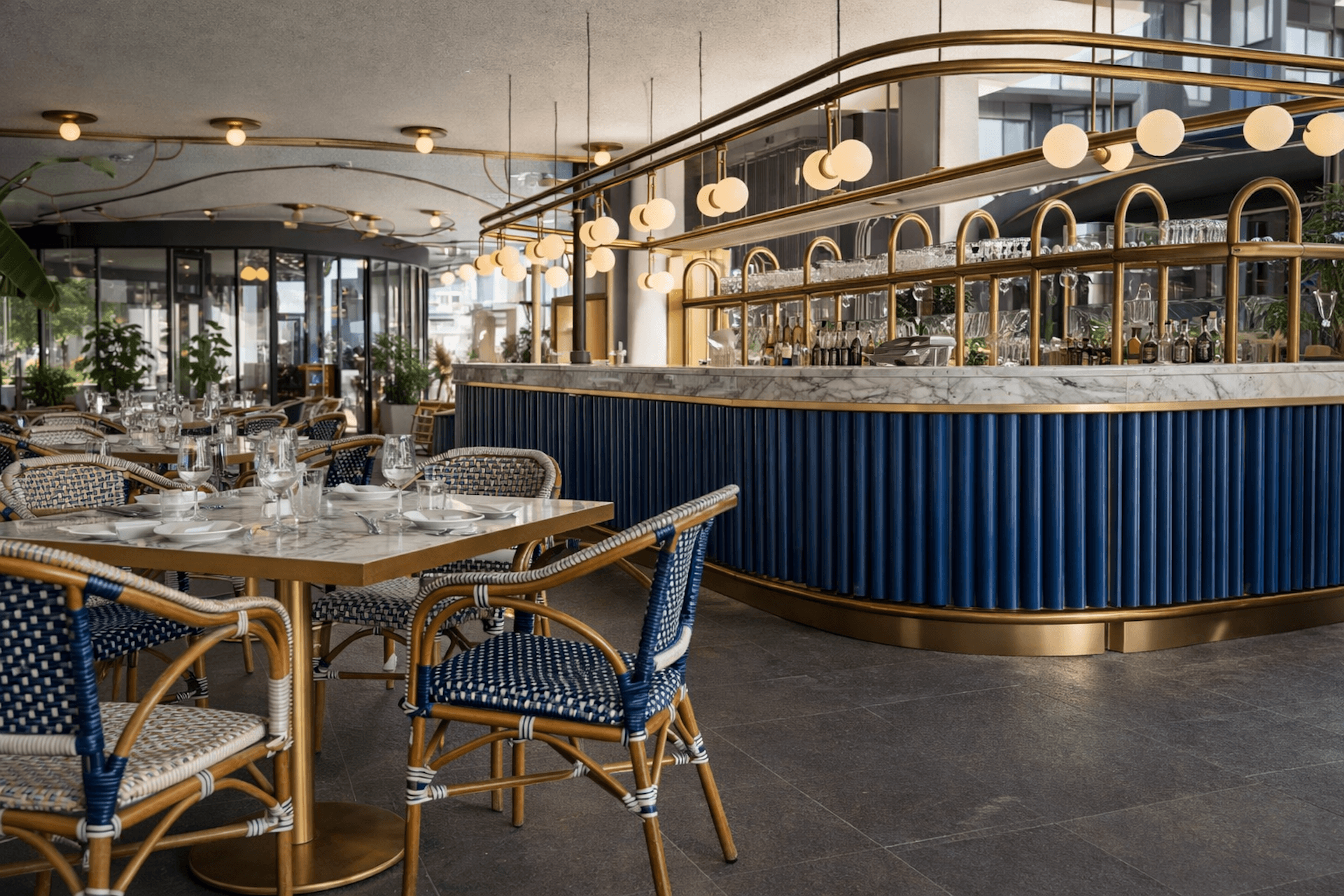 Modern elegant restaurant dining area with blue and gold accents, pendant lighting, and bar counter