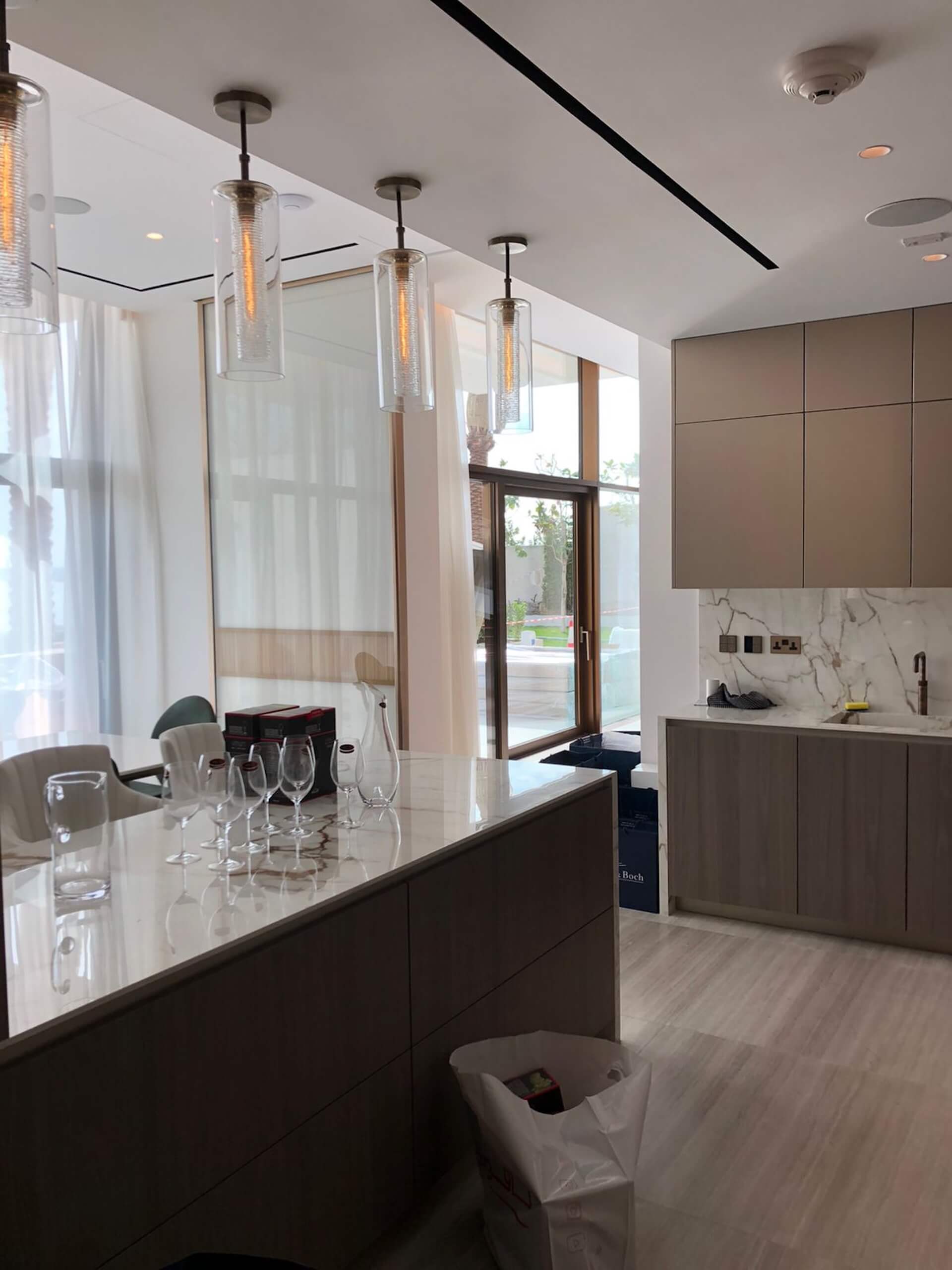 Modern kitchen with dark cabinetry, white quartz countertops, pendant lights, and glass backsplash.