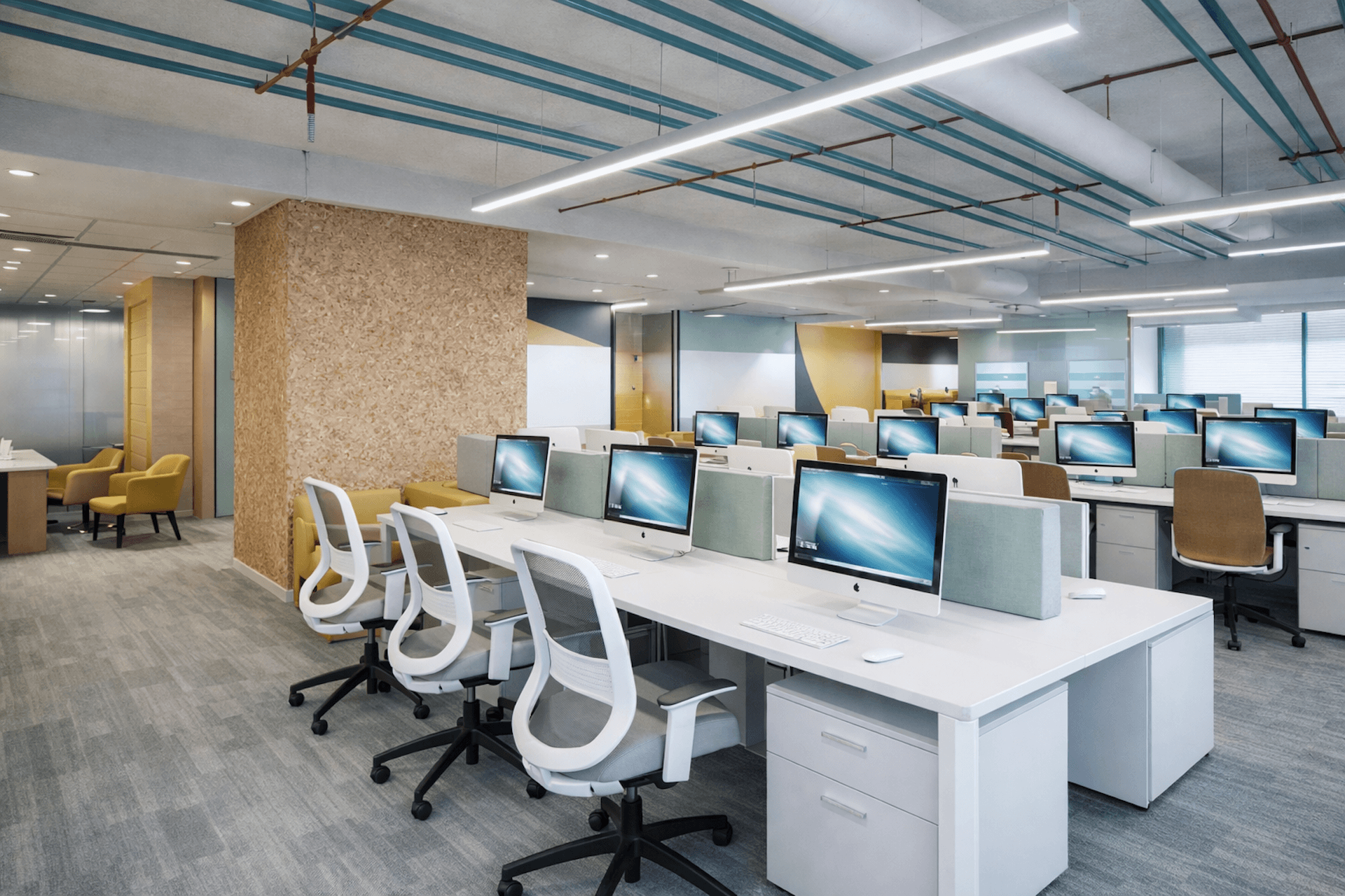 Modern office space with white chairs, computers, and cork accent wall.