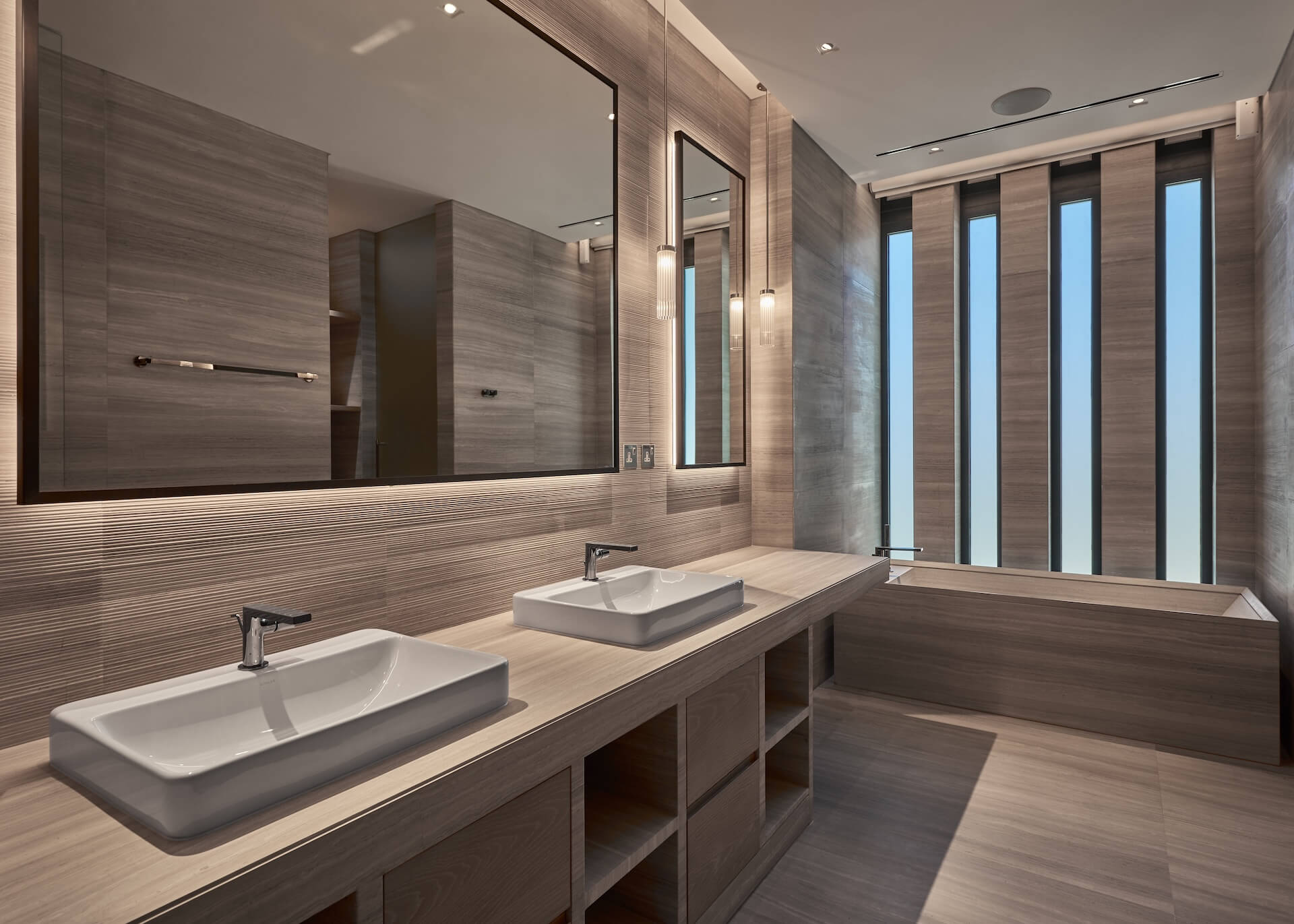 Modern luxury bathroom with dual sinks, large mirrors, and wooden finishes throughout