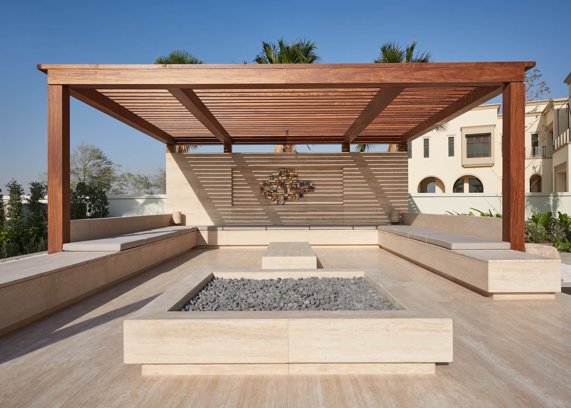 Modern rooftop terrace with wooden pergola, fire pit, and Mediterranean-style architecture