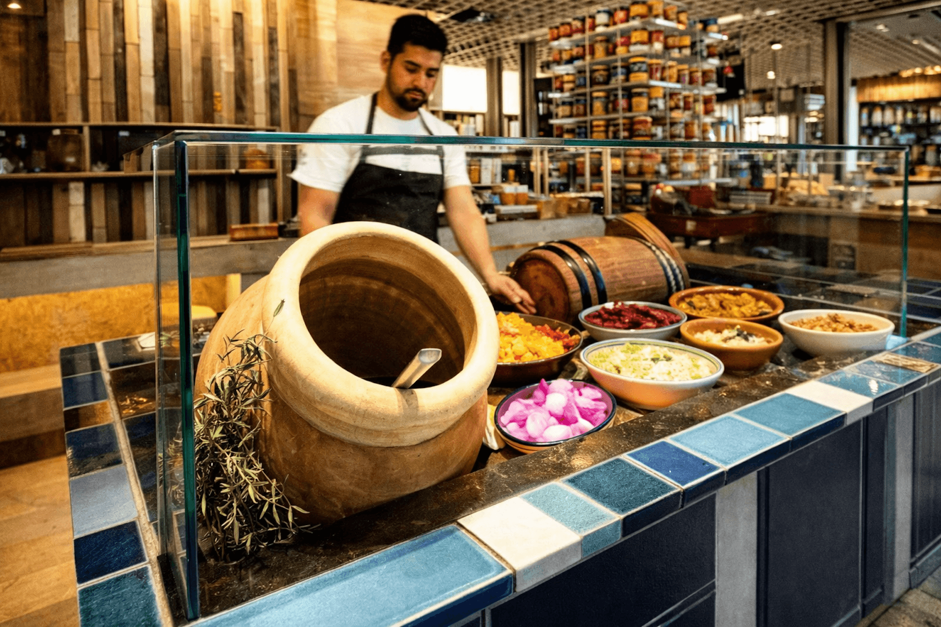 Chef displays traditional ingredients and pottery in Middle Eastern restaurant kitchen display