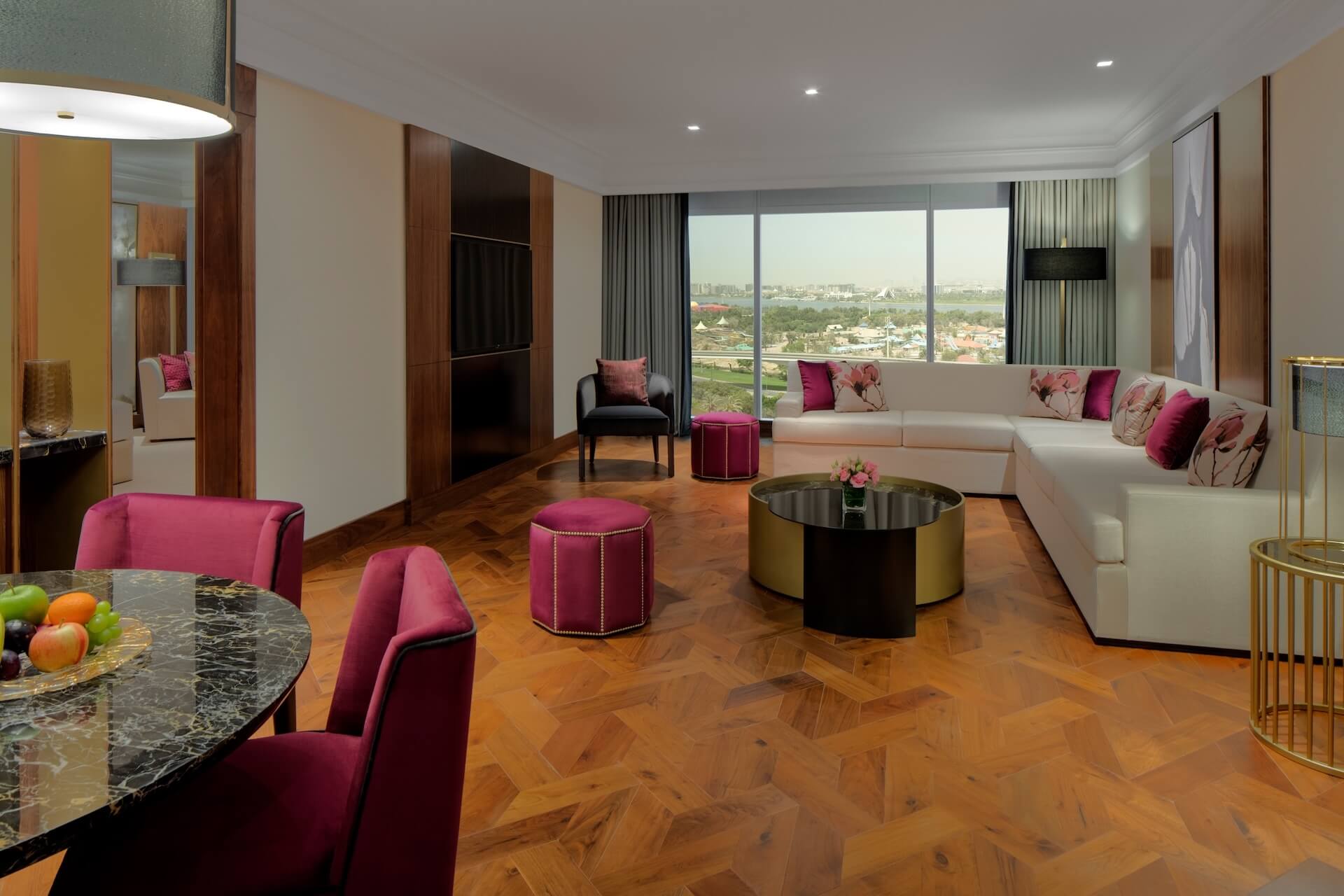 Luxury apartment living room with pink accents, wooden floors, and city skyline views.