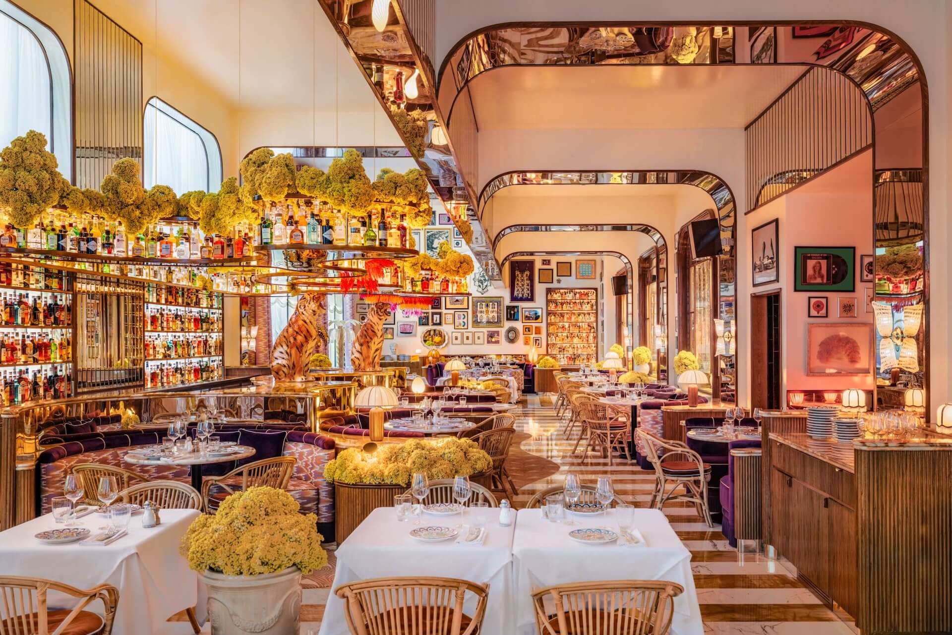 Luxurious restaurant interior with elegant dining tables, yellow flowers, and warm golden lighting throughout.