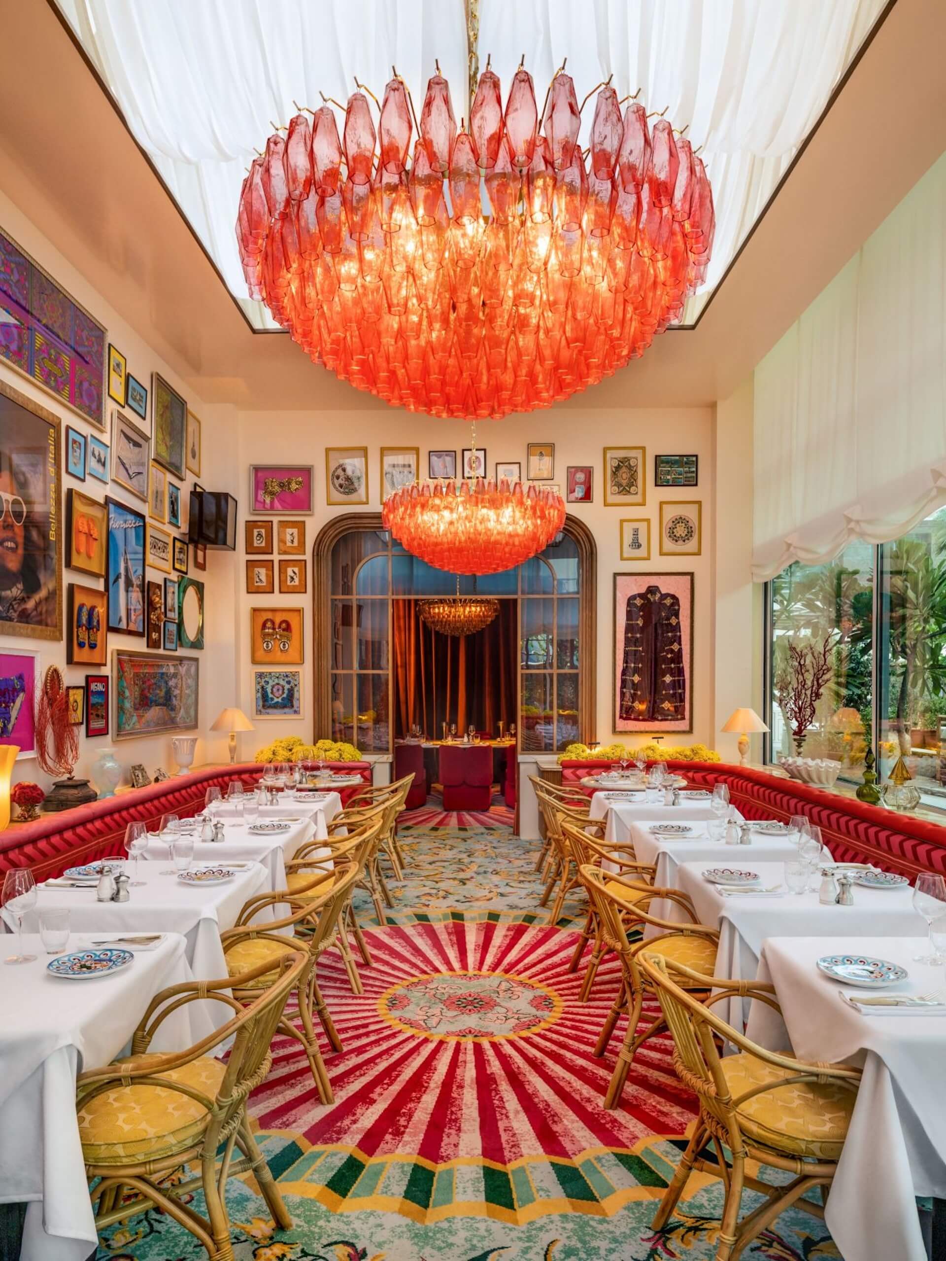 Luxurious dining room with red glass chandeliers, gold chairs, colorful artwork walls.