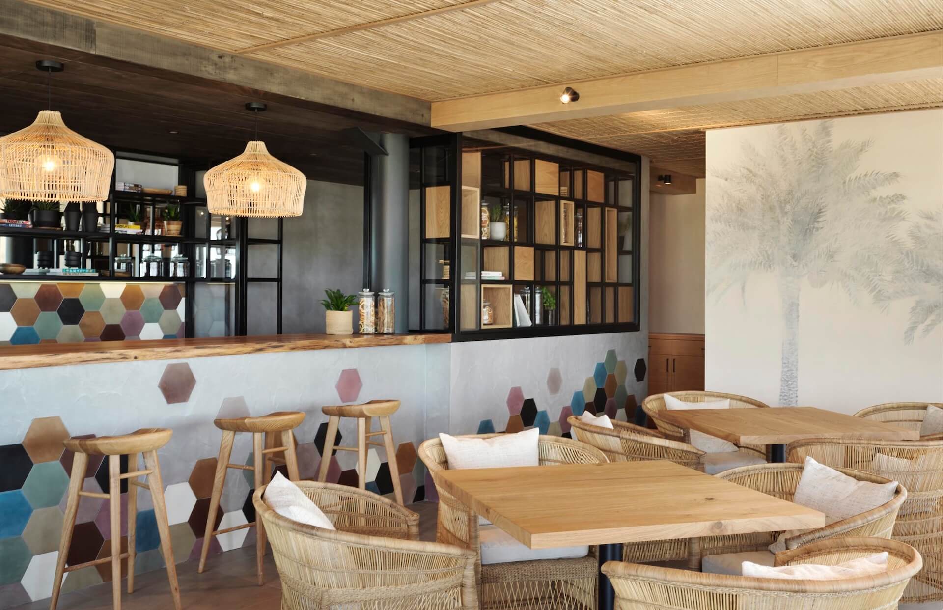 Modern cafe interior with wooden tables, wicker chairs, and colorful hexagonal tile accent wall
