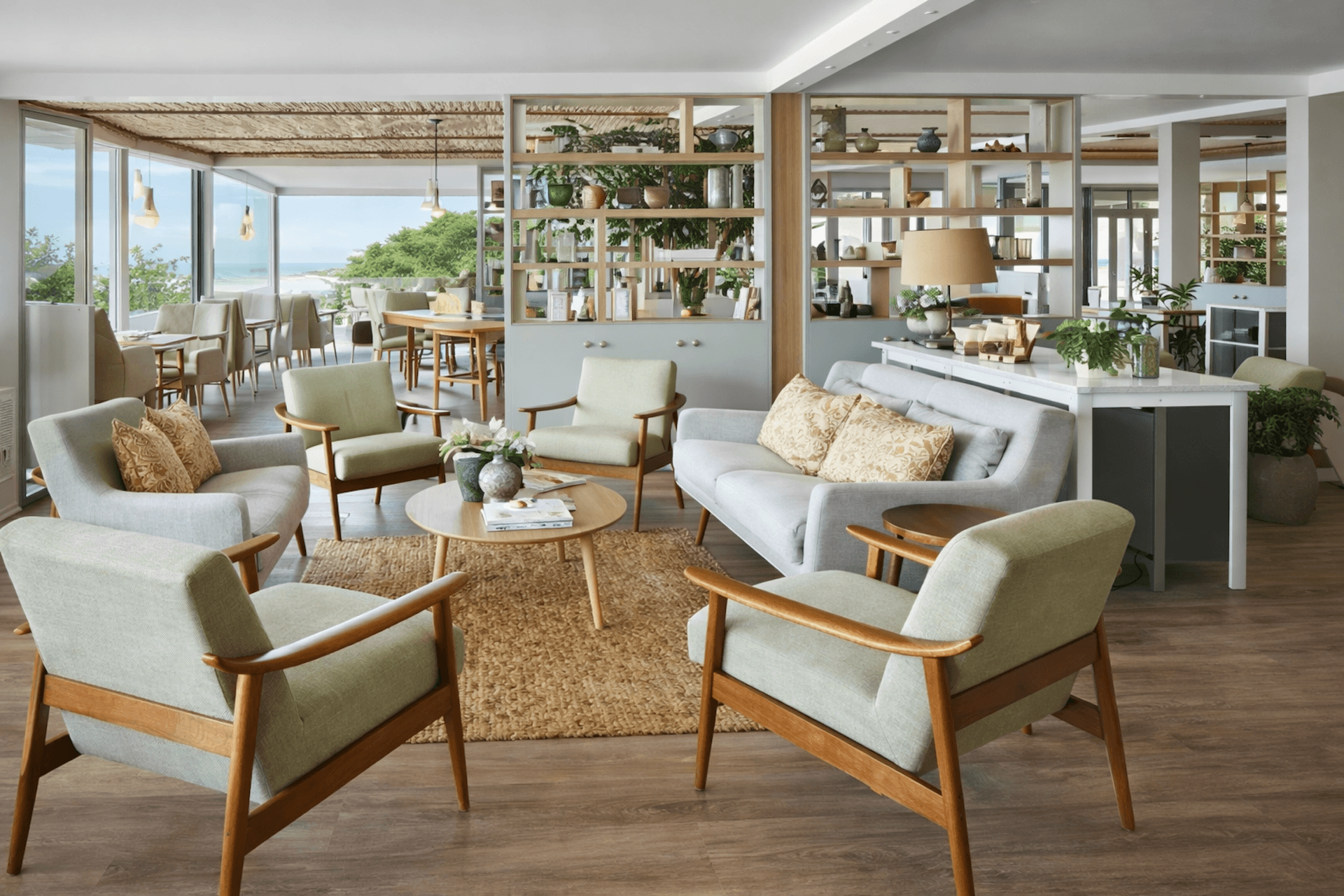 Modern coastal living room with mid-century furniture, wooden shelving, and ocean view