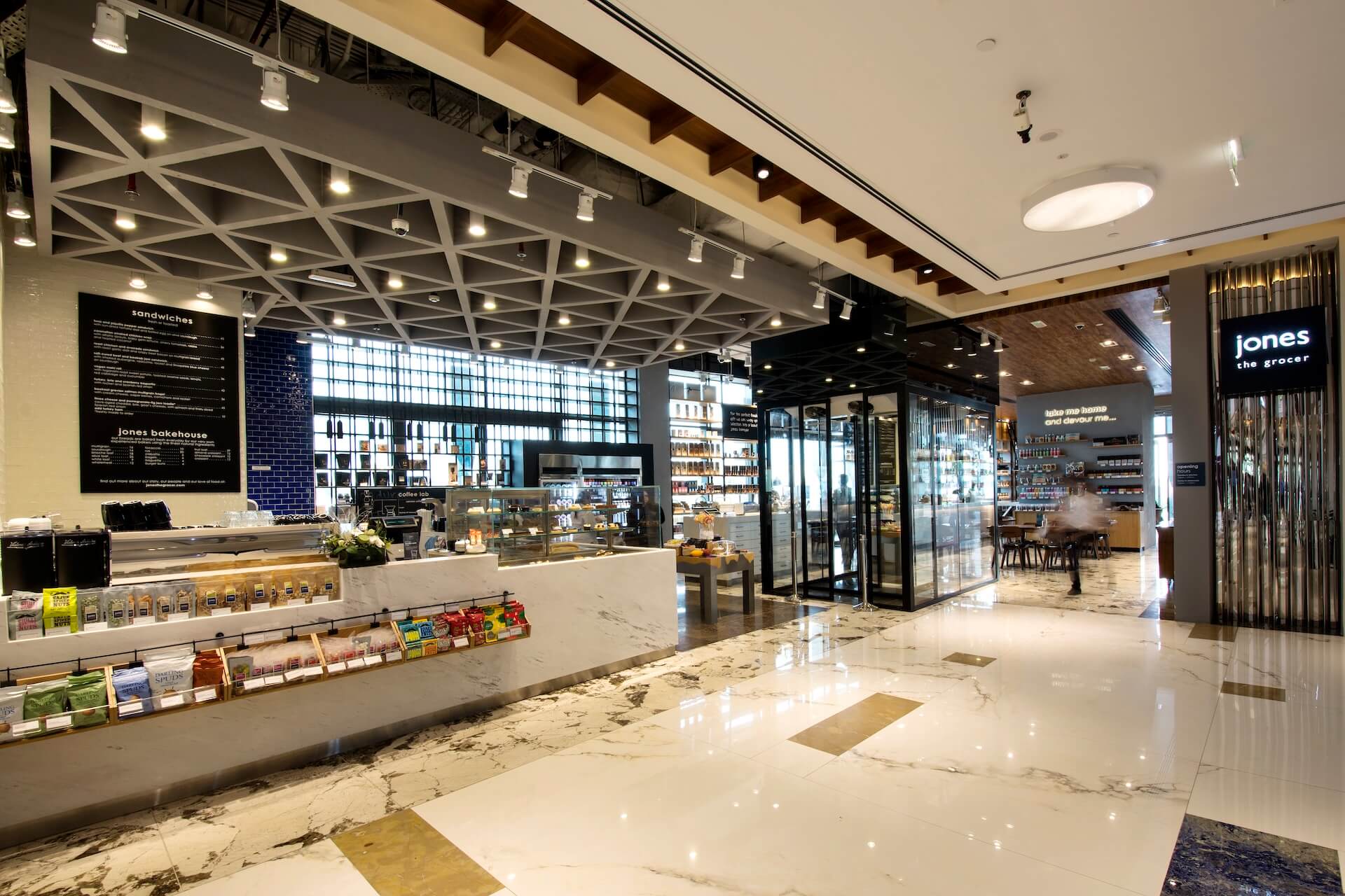 Modern bakery and grocery store interior with marble counters and contemporary lighting fixtures.
